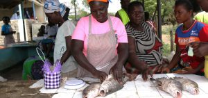 <p>Ida Odhiambo (in pink) guts a nile perch, ready to extract its maw. (Photo: Geoffrey Kamadi)</p>