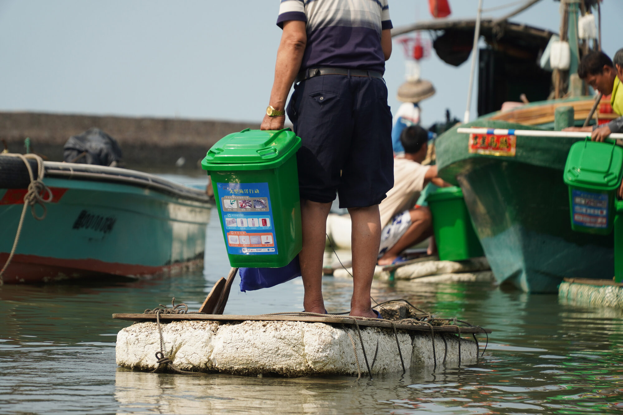 A fisher in Hainan transports a new waste bin to his boat.