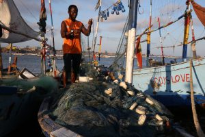 <p>加纳首都阿克拉附近的詹姆斯敦，一位渔民正在整理渔网。加纳水域的非法捕捞活动给该国小规模手工渔民带来的压力越来越大。但是这些渔民也表示，打击非法捕捞的“一揽子政策”会破坏他们的生计。 （图片来源：<a href="https://www.flickr.com/photos/worldbank/21543739454/in/album-72157605944694861/">Dominic Chavez</a>/世界银行，CC BY-NC-ND 2.0）</p>
