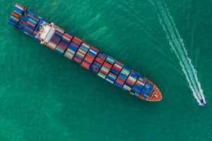 a cargo ship carrying multi-stack of containers in sea crossing international waters an aerial view, Singapore